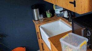 Eine kleine Küche mit Spüle, Mikrowelle, Wasserkocher und Wasserspender.