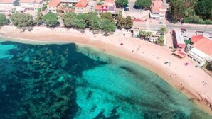 An aerial view of a coastal area with a beach, clear water, and buildings along the shore. - Villa *** 120m² | sea view | 800m from the beaches (Les Issambres)