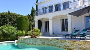 A pool with clear water, a white building with a balcony, and a stone wall. - Villa *** 120m² | sea view | 800m from the beaches (Les Issambres)