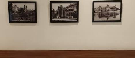 A hotel room with a wooden headboard, a large bed with white linens, and three black-and-white photographs on the wall.
