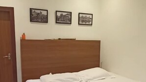 Ein Schlafzimmer mit einem hölzernen Bett, weißer Bettwäsche und einem gerahmten Bild auf dem Bett.