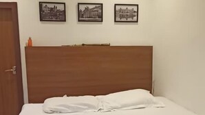 Ein Hotelzimmer mit einem Bett, einem hölzernen Kopfteil und drei schwarz-weißen Bildern in Rahmen an der Wand.