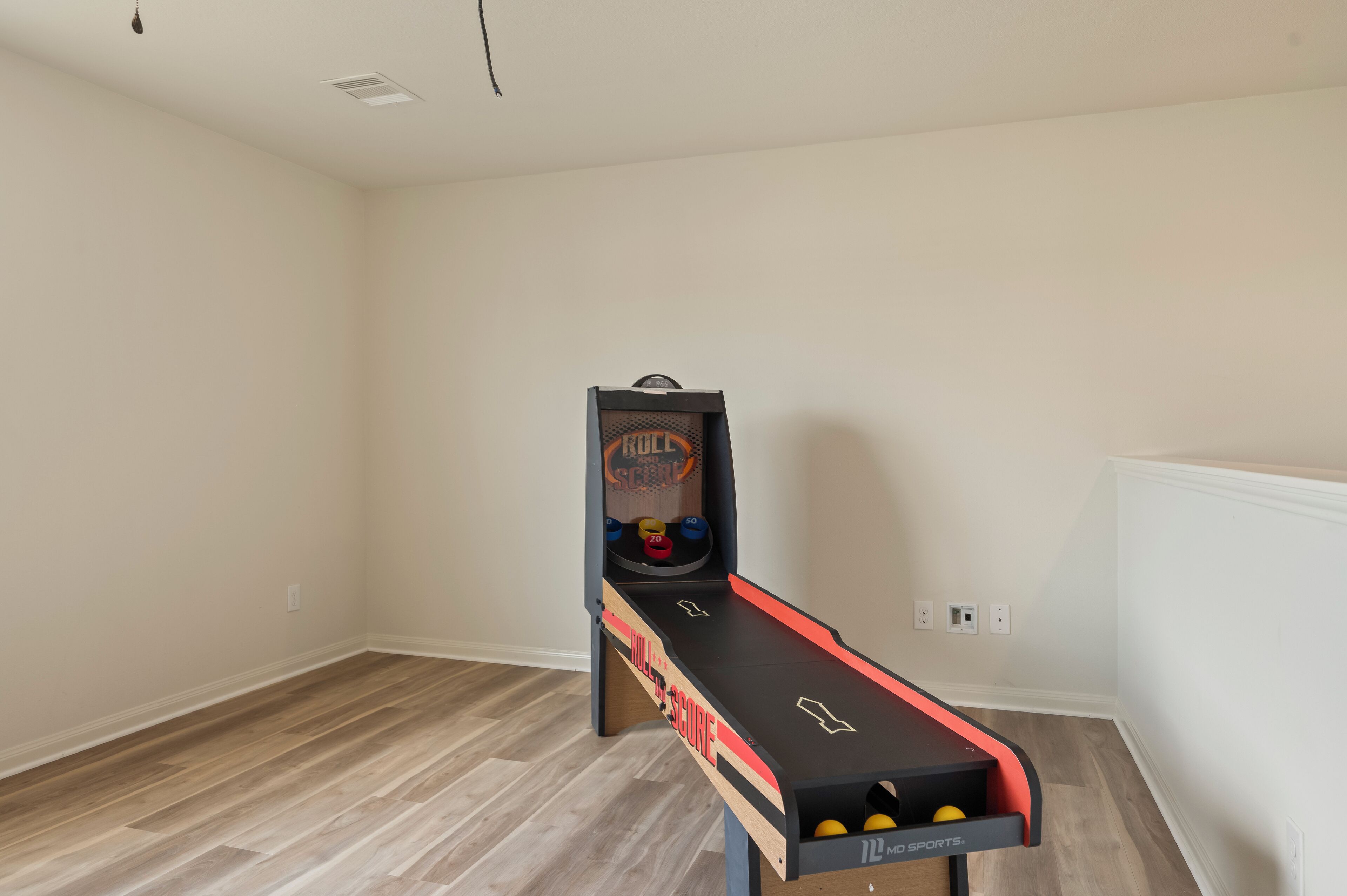 Huone, jossa on shuffleboard-pöytä, koripallokehä ja pieni koripallokenttä.
