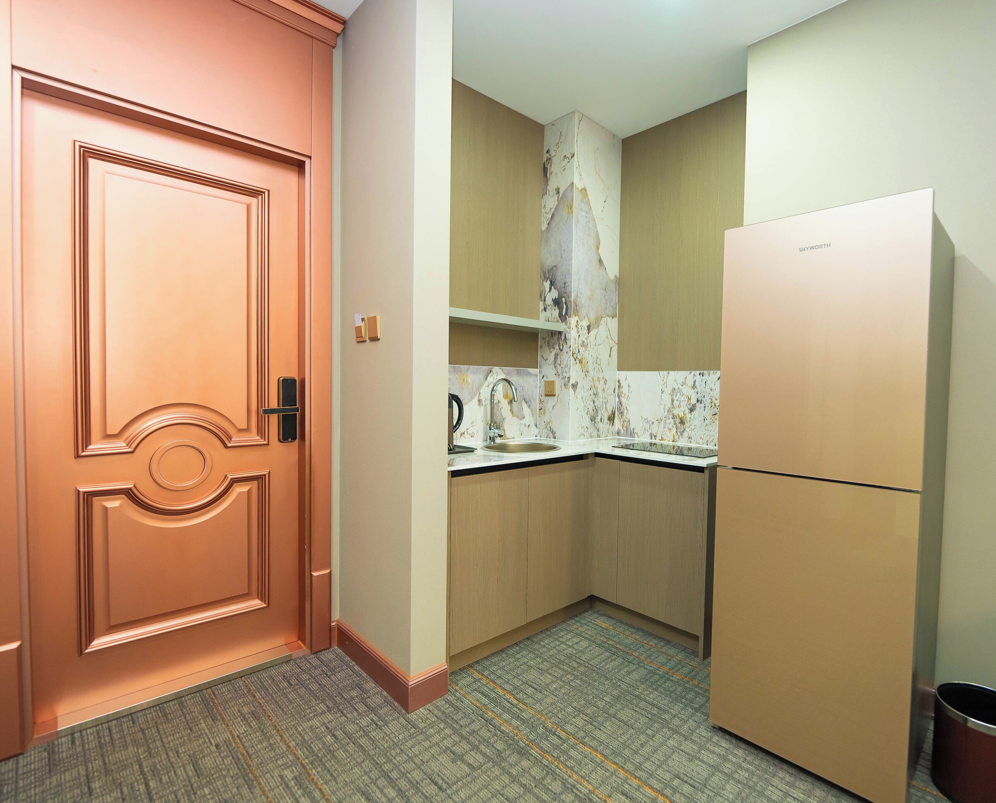 A compact kitchen with a marble backsplash, a built-in oven, and a refrigerator.