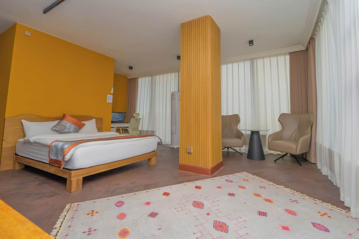Una habitación de hotel con cama, escritorio, silla y una mesita.