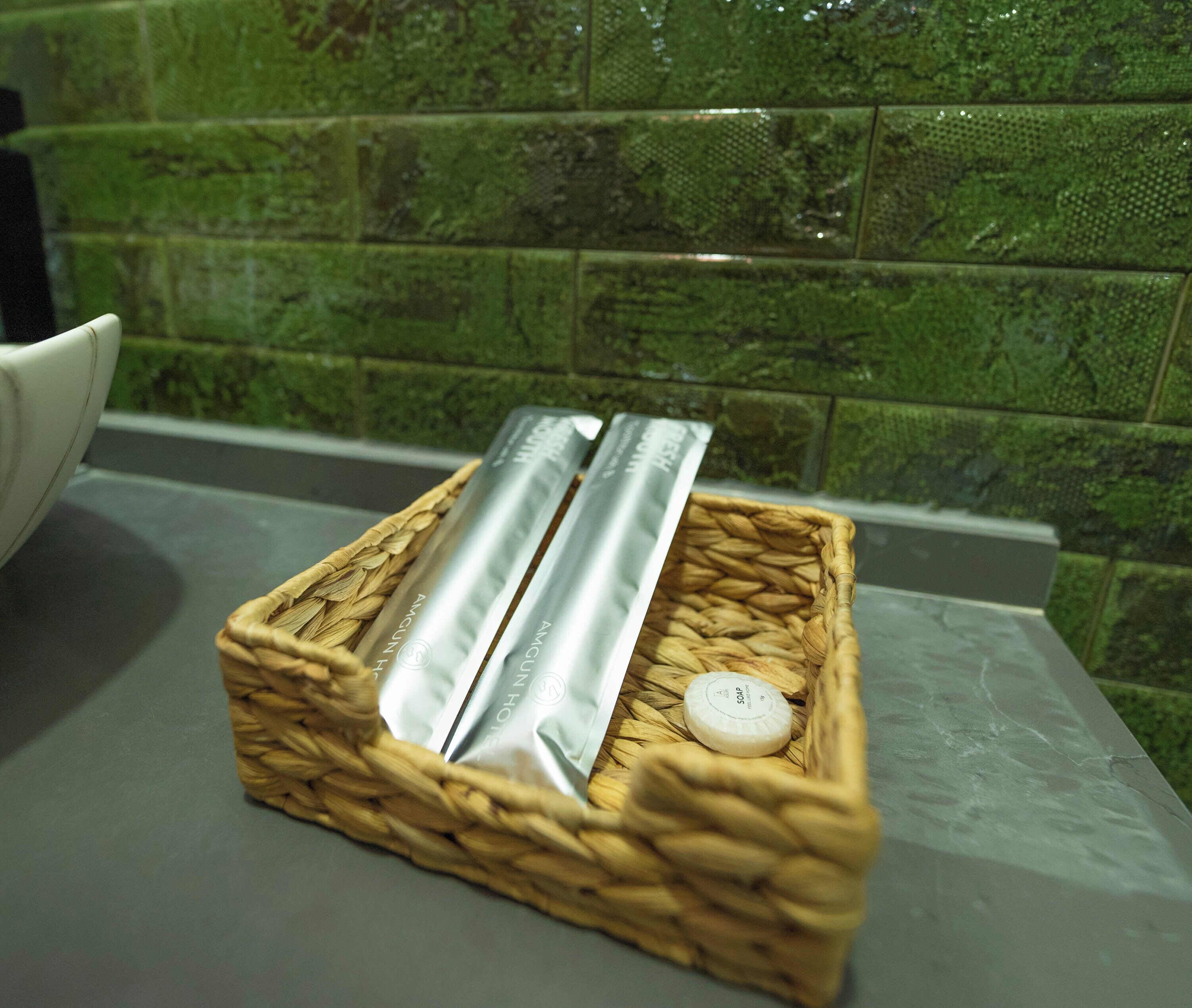 A woven basket containing two silver containers and a small white object on a countertop.