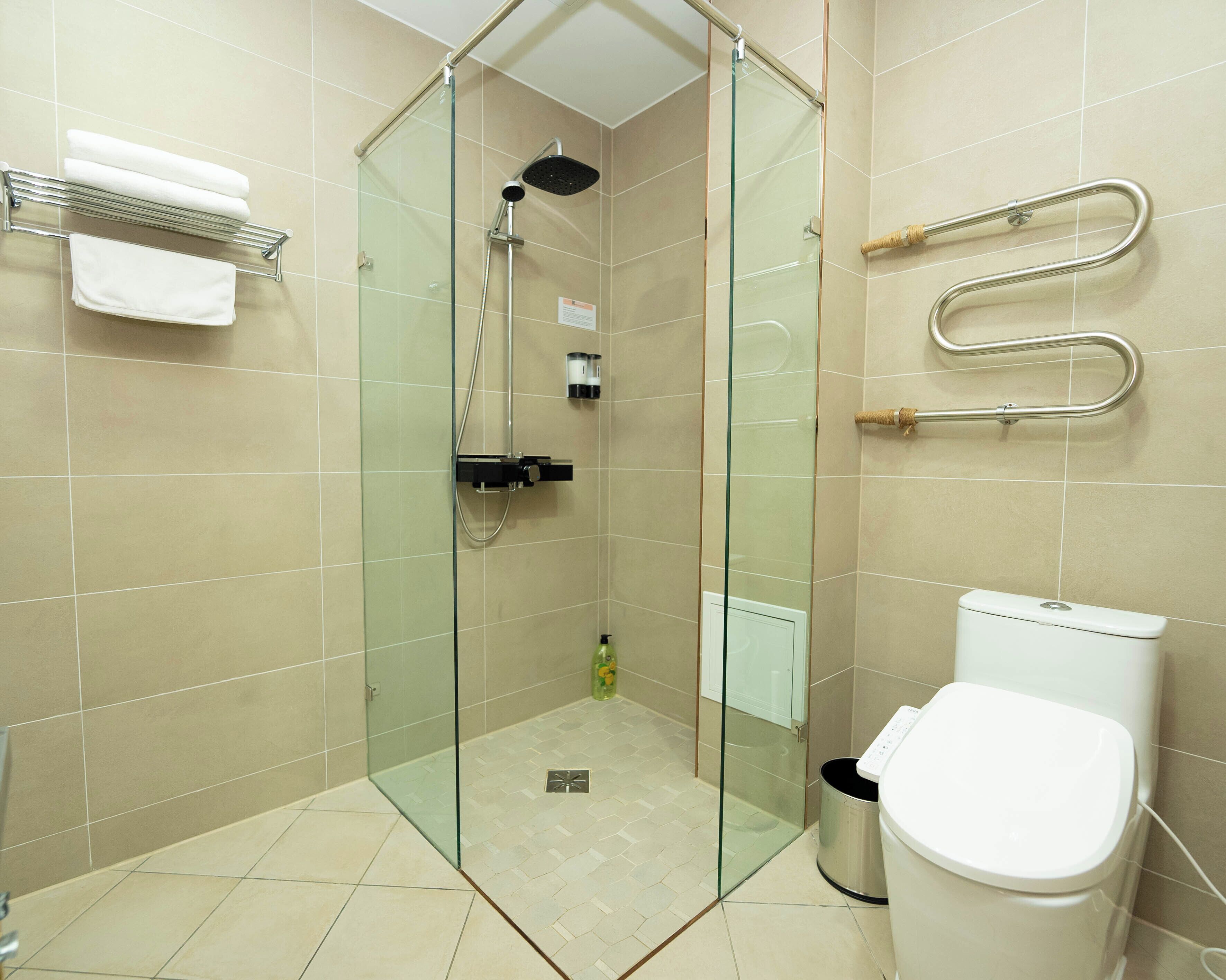 Un baño moderno con ducha envuelta en vidrio, inodoro y perchero.