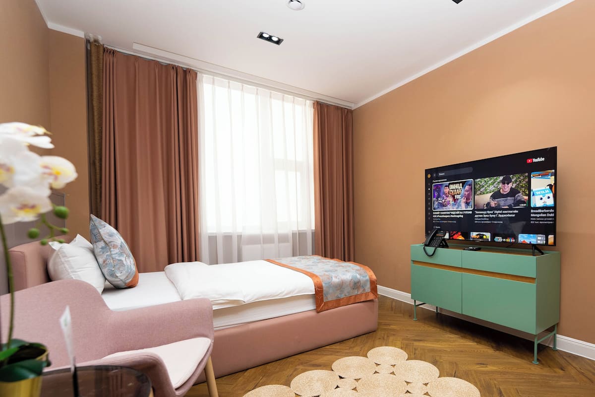 Un dormitorio moderno con cama, televisor, escritorio y silla.