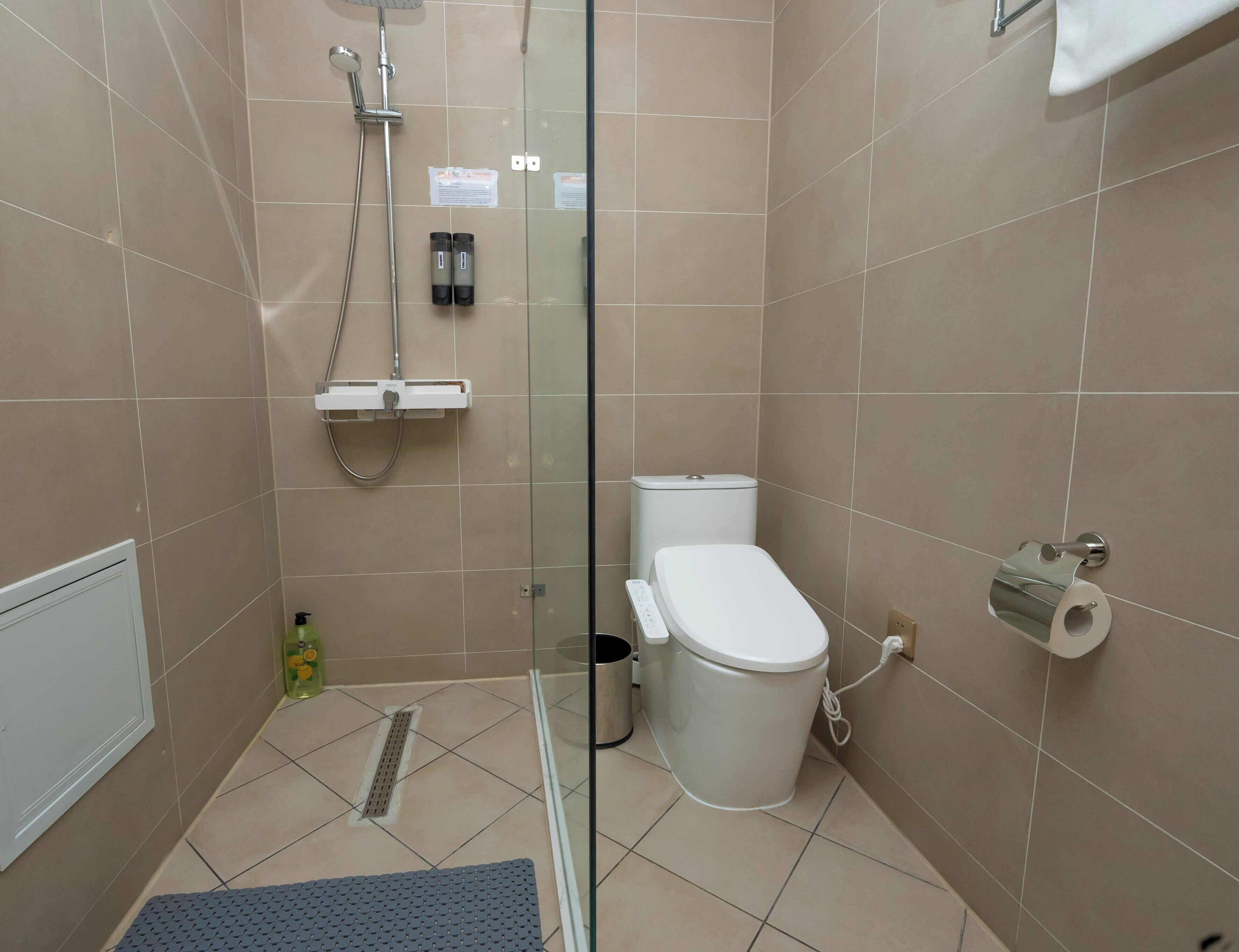 Une salle de bain moderne avec une douche à parois de verre, des toilettes et un sèche-mains.