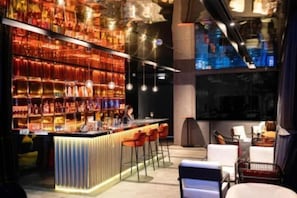 Eine Bar mit Theke, Hockstühlen und Flaschenregalen.