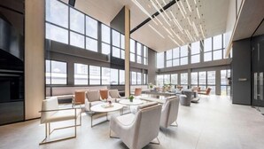 A spacious, modern lounge area with large windows, comfortable seating, and a clean, minimalist design. - Ramada by Wyndham Bangkok Sukhumvit 87 (Bangkok)