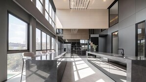 A modern kitchen with a long counter, large windows, and a view of the outdoors. - Ramada by Wyndham Bangkok Sukhumvit 87 (Bangkok)