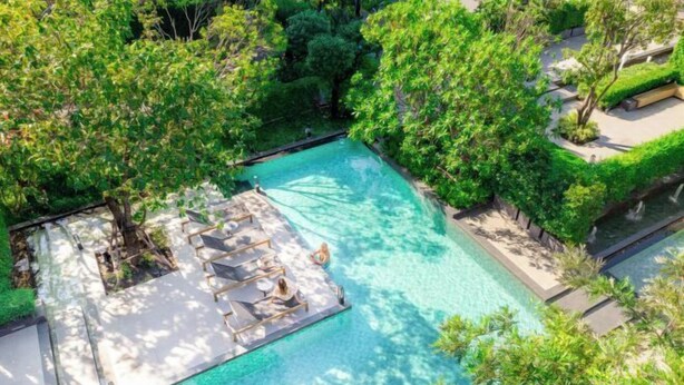 An aerial view of a swimming pool surrounded by lush greenery and a small deck area with lounge chairs. - Ramada by Wyndham Bangkok Sukhumvit 87 (Bangkok)