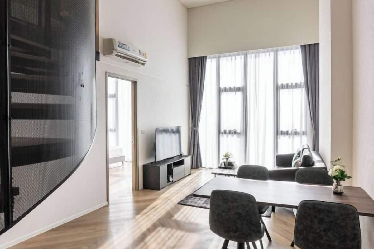A modern living room with a TV, seating area, and a dining table.