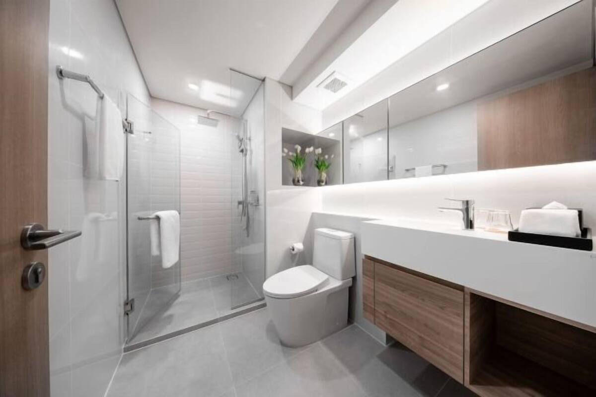 A modern bathroom with a glass shower enclosure, a toilet, and a vanity with a mirror.