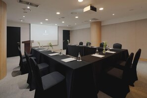 A conference room with a long table, chairs, a projector screen, and a podium. - Amid Hotel Seoul (Seoul)
