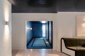 A hallway with a blue-tiled floor, a dark ceiling, and a green sofa. - Amid Hotel Seoul (Seoul)