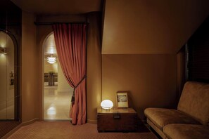A warmly lit room with a sofa, a small table with a lamp, and a curtain. - Amid Hotel Seoul (Seoul)