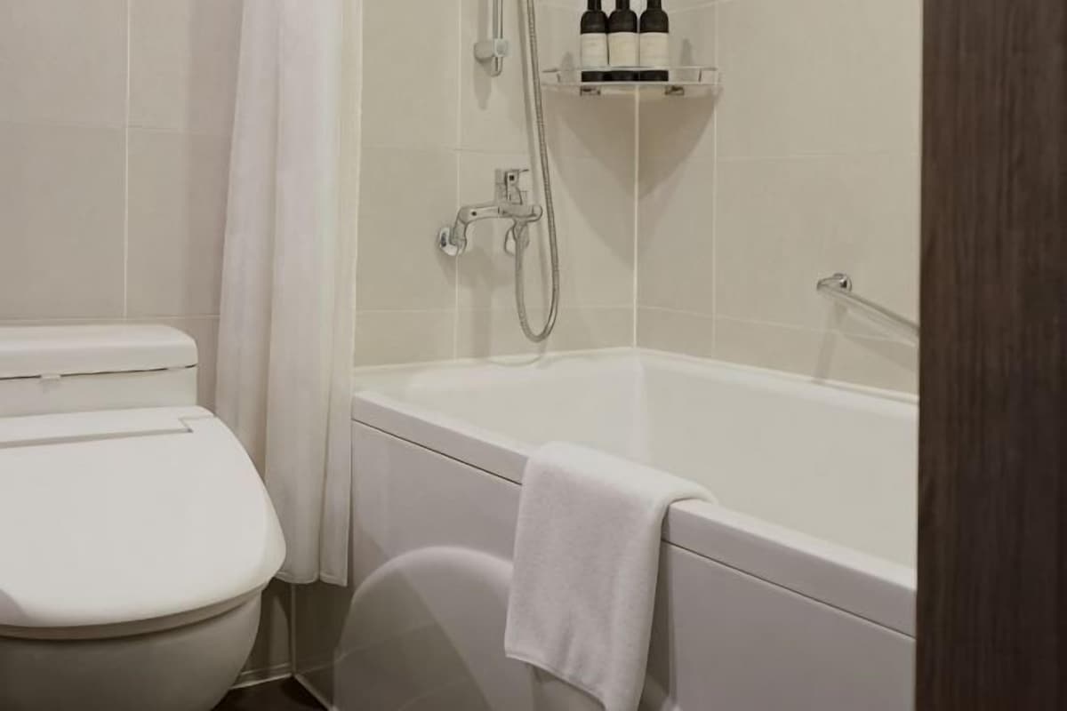 A bathroom with a toilet, bathtub, and shower.