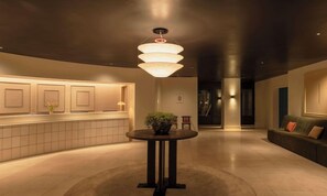 A modern lobby with a round table, a potted plant, and a unique ceiling light fixture. - Amid Hotel Seoul (Seoul)