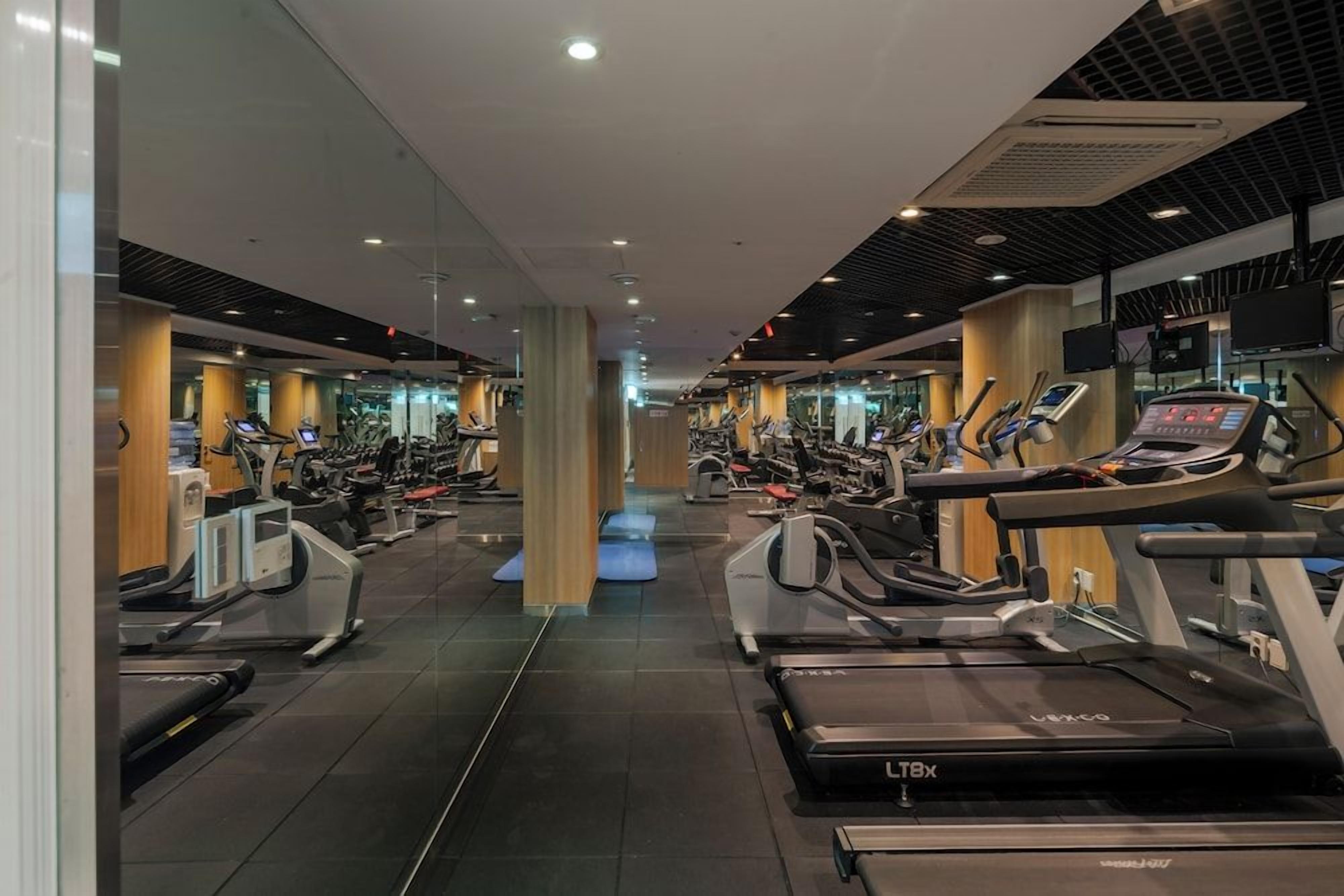 Un gimnasio con múltiples cintas de correr, bicicletas estáticas y elípticas.