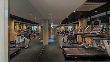 Un gimnasio con múltiples cintas de correr, bicicletas estáticas y elípticas.