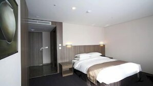 A hotel room with a bed, bedside tables, a mirror, and a door. - Amid Hotel Seoul (Seoul)