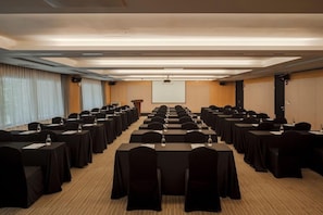 A conference room with rows of tables and chairs, a podium, and a projection screen. - Amid Hotel Seoul (Seoul)