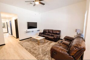 Una sala de estar con un sofá, una mesa de centro y un televisor montado en la pared.