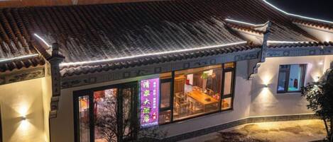 A traditional building with a tiled roof and illuminated signage.
