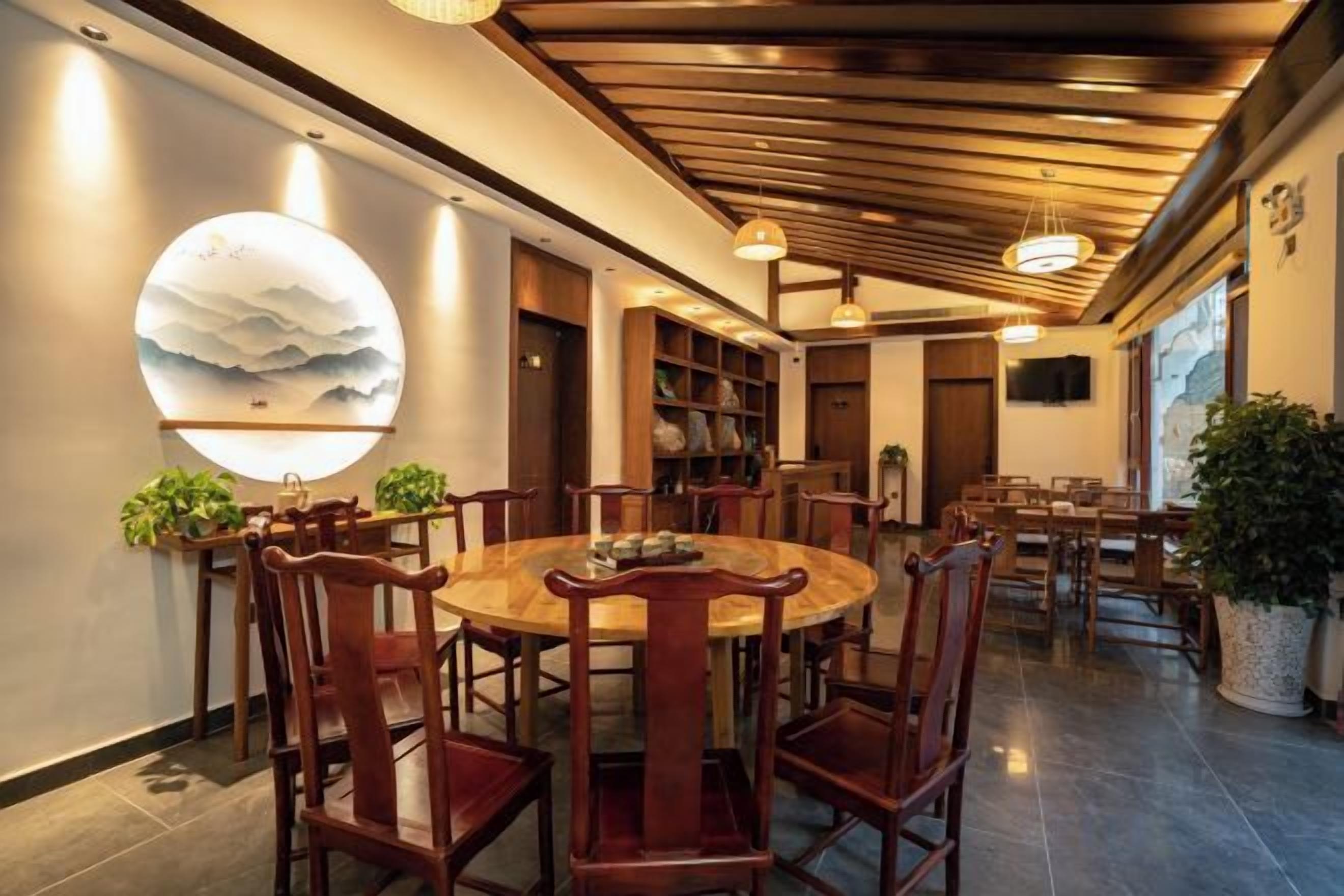 Un comedor con una mesa redonda de madera y sillas, un globo terráqueo en la pared, y un techo con vigas de madera.
