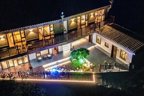 Een gebouw met twee verdiepingen, een balkon, een kleine tuin en buiten zitplaatsen.