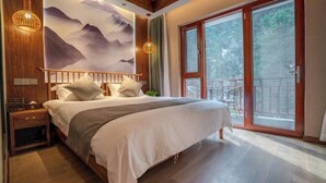 A bedroom with a bed, wooden headboard, nightstands, a wall mural, and a sliding glass door to a balcony. - Jiu Hua Qing Quan Hotel (Qingyang)