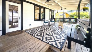 A covered porch with a ceiling fan, a wooden bench, and a patterned rug. - King William Charm 2-bedroom house in welcoming San Antonio with AC (San Antonio)