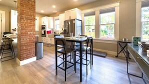 A modern kitchen with white cabinets, a brick column, and a dining area with two chairs. - King William Charm 2-bedroom house in welcoming San Antonio with AC (San Antonio)
