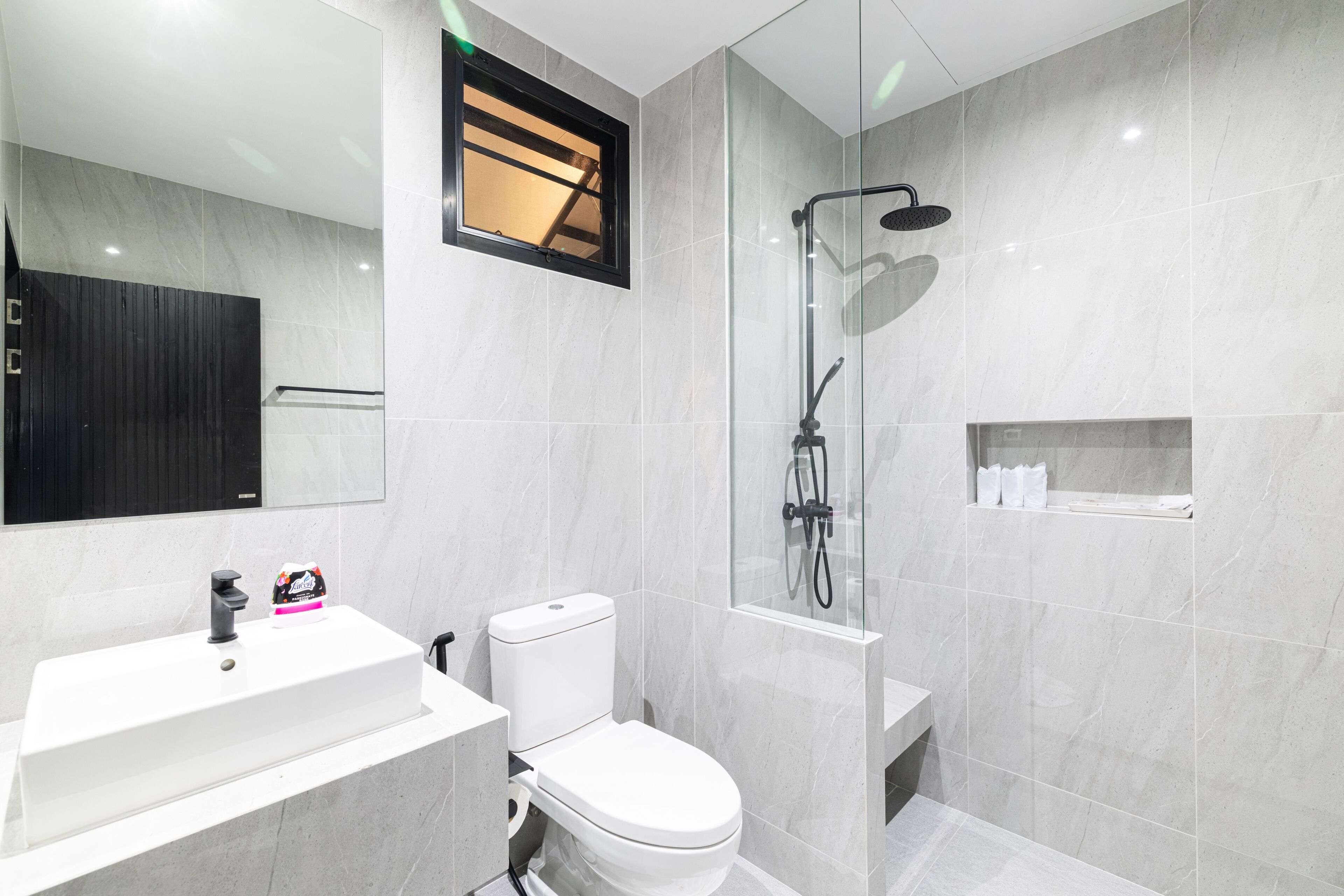 Une salle de bain moderne avec un lavabo blanc, des toilettes et une douche à parois de verre.
