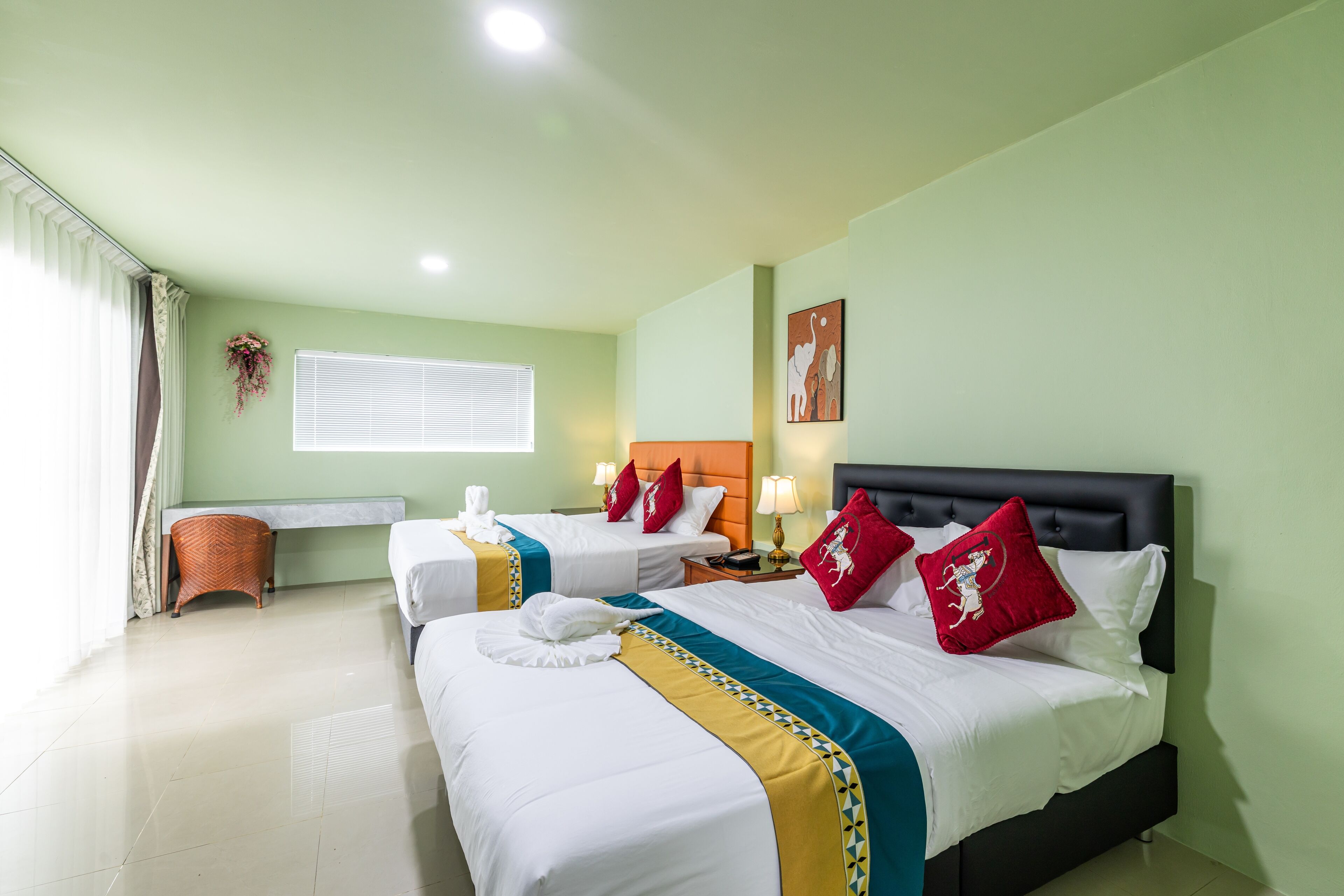Una habitación de hotel con dos camas, un escritorio y una ventana con cortinas.