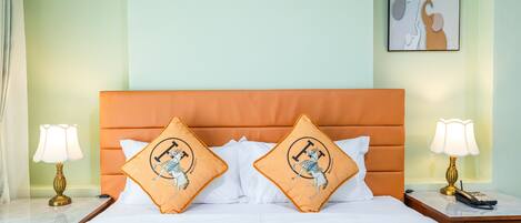A neatly made bed with two decorative pillows, a bedside table with a lamp, and a framed artwork on the wall.