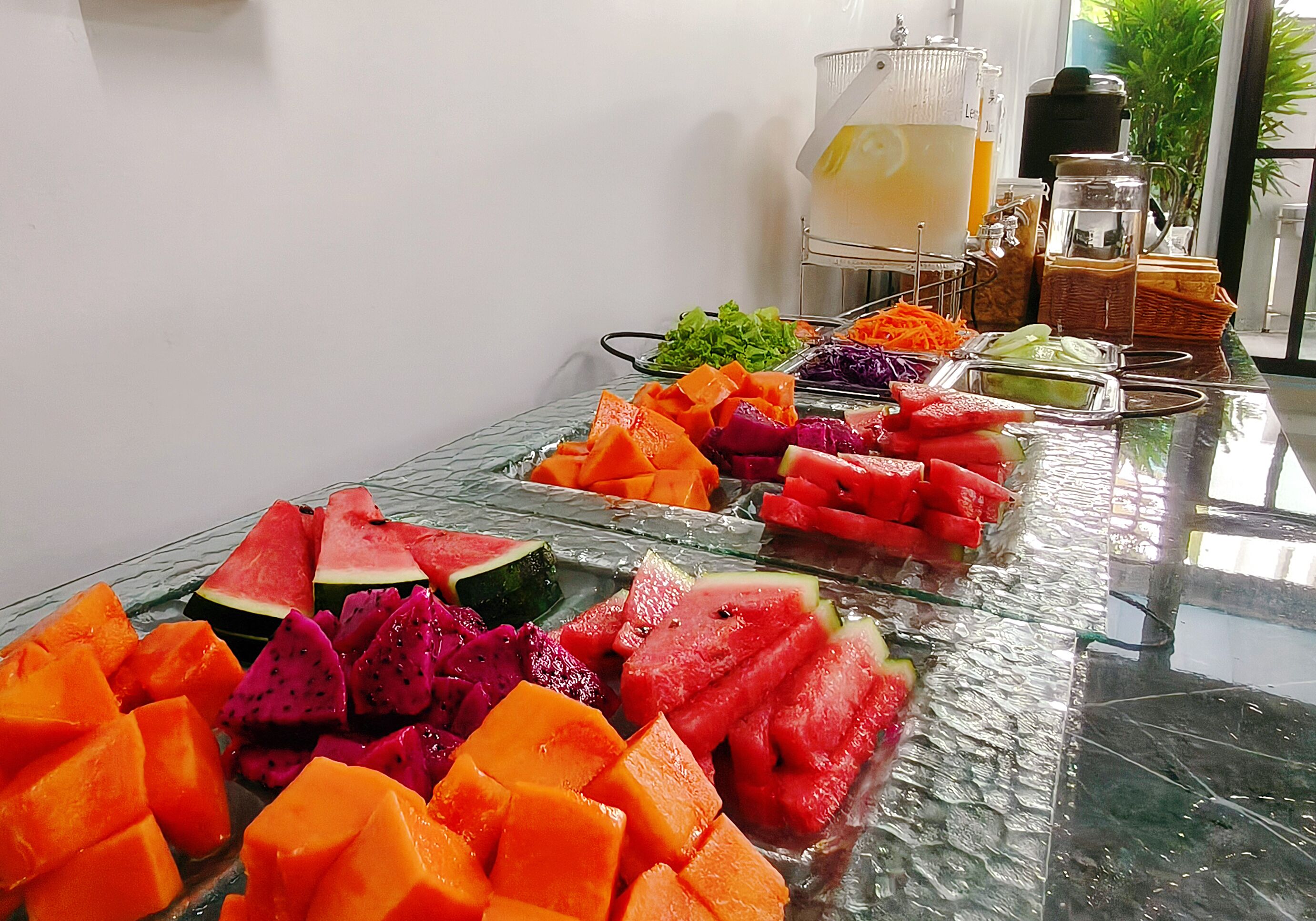 A buffet table with various fruits and a beverage station.