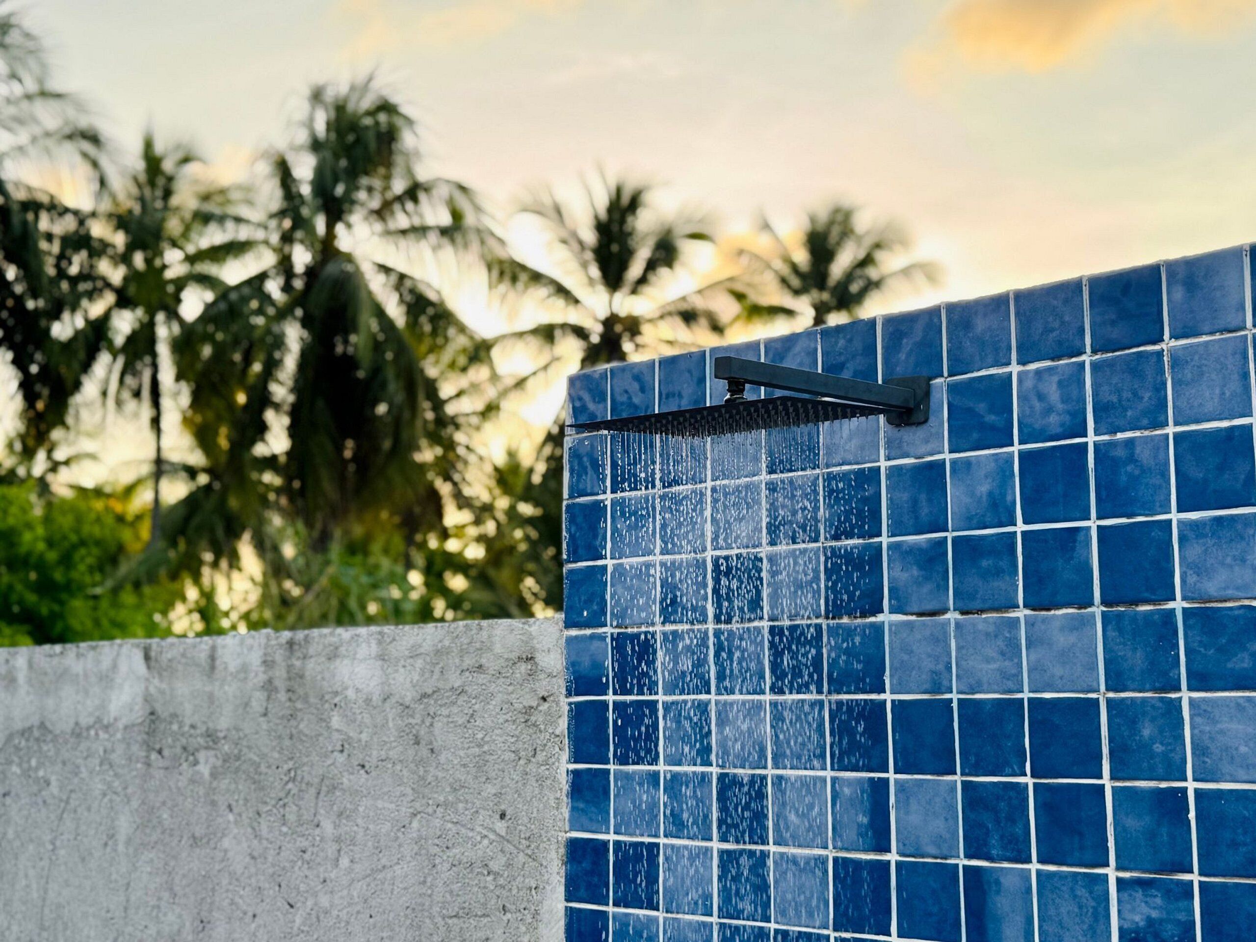 A blue tiled wall with a showerhead.