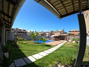 Un jardin à l’arrière d’une maison, avec une piscine, un espace patio et une vue sur les bâtiments voisins.