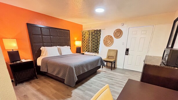 A hotel room with a bed, bedside tables, a chair, a desk, and a television.