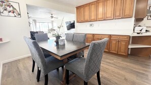A modern kitchen with wooden cabinets, a dining table with chairs, and a ceiling fan. - Entire Newly Remodeled Home With Huge Parking (Quartz Hill)