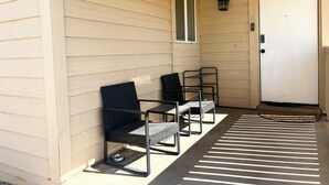 A covered porch with two chairs and a table, a door, and a window. - Entire Newly Remodeled Home With Huge Parking (Quartz Hill)