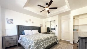 A bedroom with a bed, a nightstand, a dresser, a ceiling fan, a mirror, and a wardrobe. - Entire Newly Remodeled Home With Huge Parking (Quartz Hill)