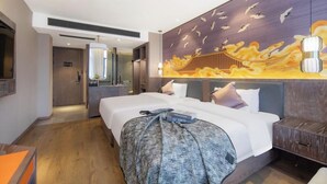 Una camera d'albergo con un letto grande, un comodino, uno specchio e una parete decorata con un murale.