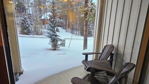 A room with a sliding glass door leading to a snowy outdoor area with trees and a wooden deck. - Rare Upper Village Townhouse w/a garage for gear and tuning! (Panorama)