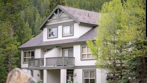 A two-story house with a balcony, surrounded by trees. - Rare Upper Village Townhouse w/a garage for gear and tuning! (Panorama)