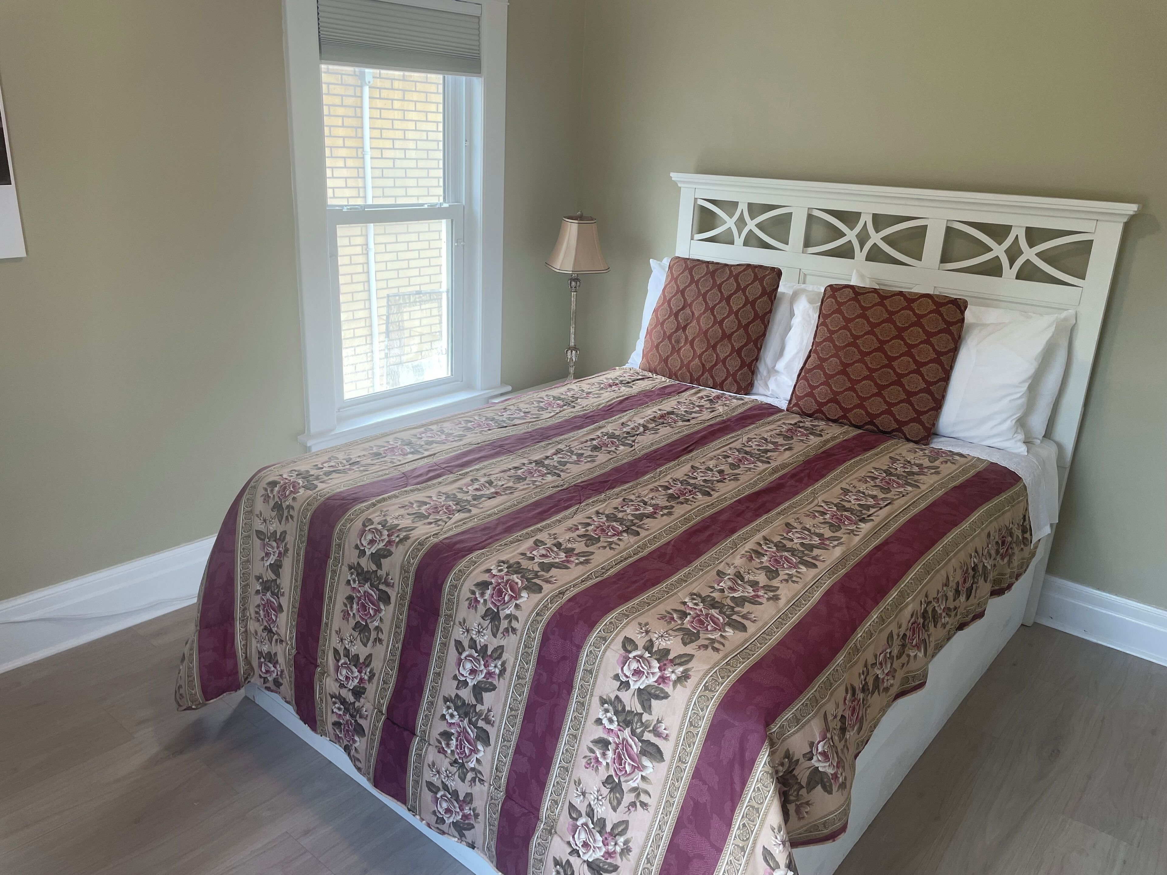 Een slaapkamer met een bed, een raam en een lamp.