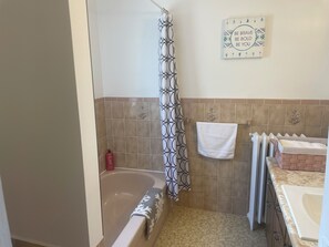 A bathroom with a bathtub, a shower curtain, a towel rack, and a decorative wall piece. - Ultra Close to the Falls (Niagara Falls)
